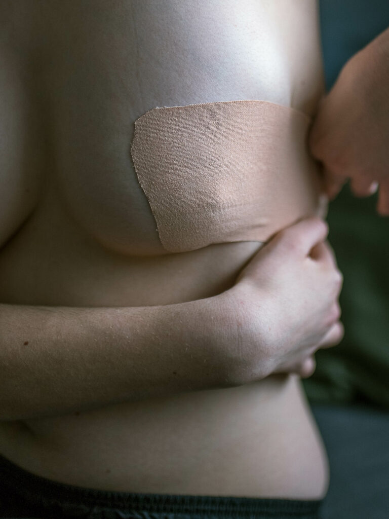 Eine Person bindet sich mit transTape die Brust ab.