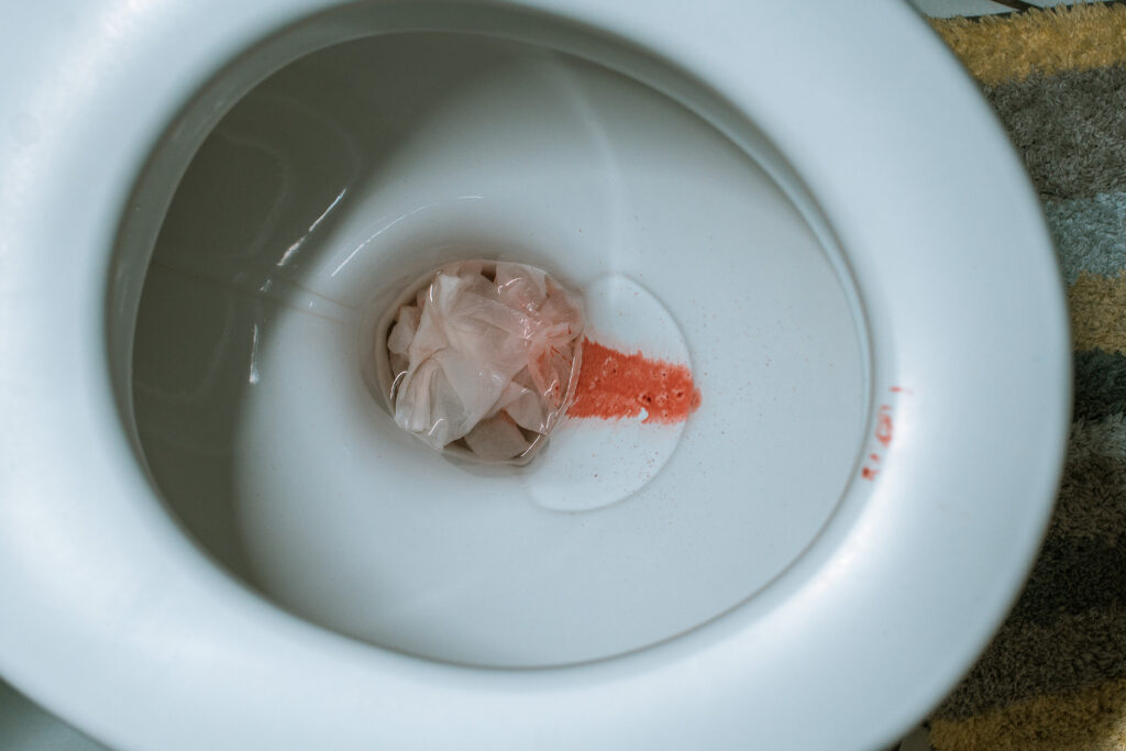 Periodenblut und Klopapier in der Toilette